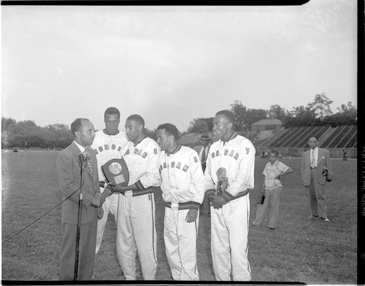 Sam Lacy, sports writer for the Afro-American newspaper, speaking with Morgan State College relay team. Paul Henderson, 1949. Maryland Historical Society.